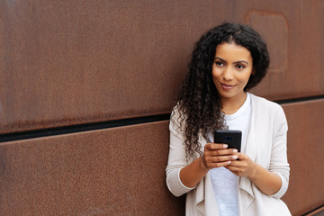 Thoughtful young woman leaning on a brown wall