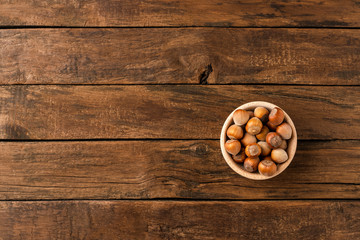 Fresh hazelnuts in bowl on wooden background with copyspace. Top view