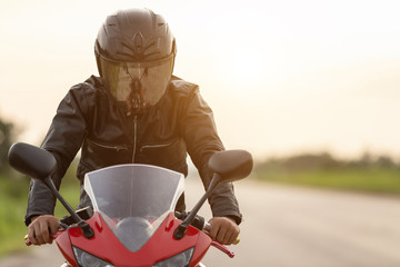 Handsome motorcyclist wear leather jacket and holding helmet on the road