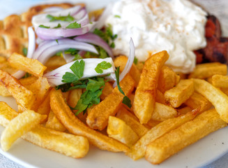 spicy kebab plate with pita bread, onions, fried potatoes, and tzatziki sauce