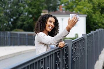 Cute young woman taking a selfie on a bridge