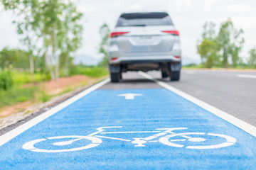 Modern car running on asphalt road / bicycle lane and tread on white bicycle sign