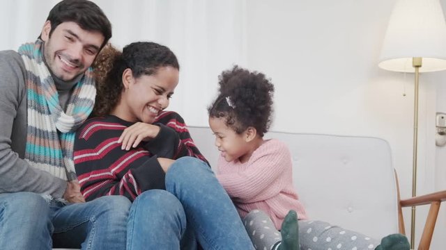 happiness caucasian and latin family play tickle together with fun joyful on sofa living room background