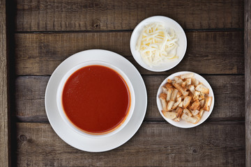 Traditional Turkish tomato soup with cheese and croutons aside isolated on rustic wooden background