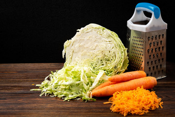 Fresh cabbage and carrot on dark wooden background. © Natallia