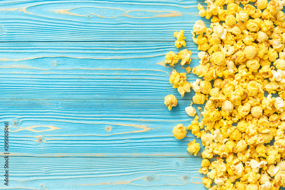 Wall mural top view yellow popcorn on blue wooden plank background