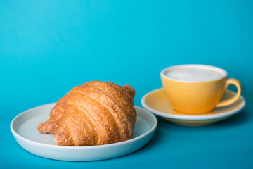 yellow cup with croissant on a blue background
