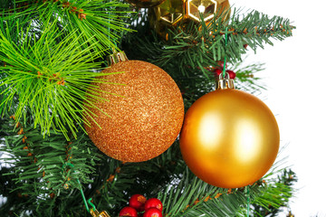 Spruce branches with golden baubles against white background