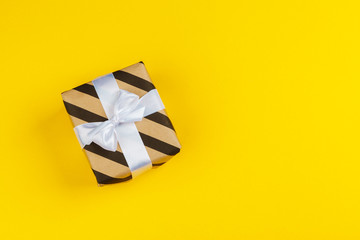 Decorated colored present on yellow background flatlay