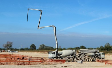 Concrete mixer trucks are going to pour concrete into the foundations  of the new building in the...