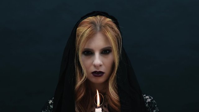 Gothic witch blows out a candle in slow motion