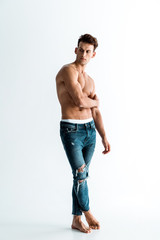 Fototapeta premium sexy man in jeans touching hand while standing on white