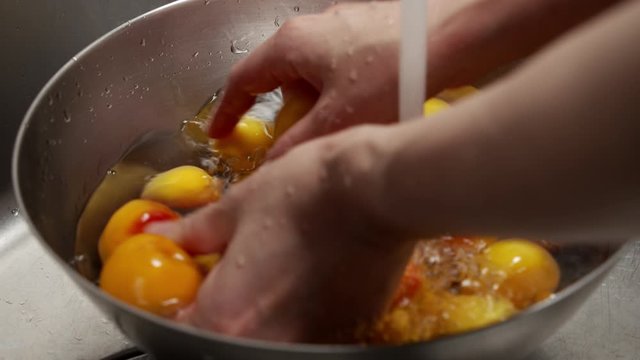 a Japanese female chef rinsing Nanko-Ume plums at her home kitchen, Tokyo, Japan. July 2019. Camera fixed, close-up, high view