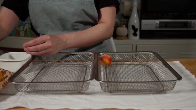 a Japanese female chef removing the stem of Nanko-Ume plums at her home kitchen, Tokyo, Japan. July 2019. Camera fixed, close-up, high view