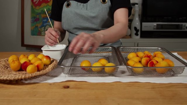 a Japanese female chef removing the stem of Nanko-Ume plums at her home kitchen, Tokyo, Japan. July 2019. Camera fixed, close-up, high view
