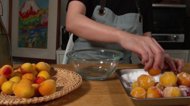 a Japanese female chef salting Nanko-Ume plums at her home kitchen, Tokyo, Japan. July 2019. Camera fixed, close-up, high view