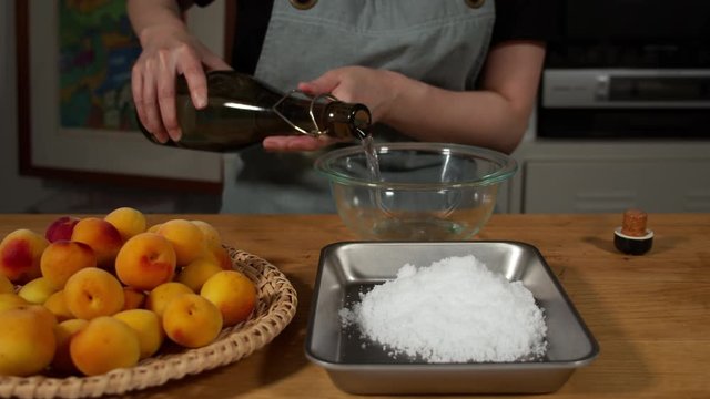 a Japanese female chef salting Nanko-Ume plums at her home kitchen, Tokyo, Japan. July 2019. Camera fixed, close-up, high view