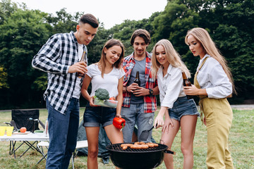 A company of friends with a drinks and food cooking on the barbecue  in the camping . - Image