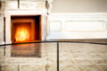 Glass table top with blurred fireplace and home interior background. Empty space background for your products and decoration.  