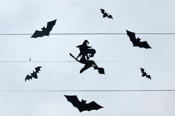 Black paper cut out bats and witch on a white wooden background. Greeting card, background, banner for the holiday Halloween.