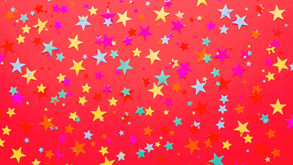 Festive red background with multicolor star shape confetti and streamers, copy space. Background...