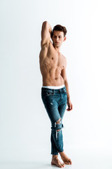 Fototapeta premium sexy man with barefoot standing in jeans on white