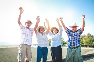 Obraz premium The elderly group of men and women in Asia visited the sea. Lift both arms with pleasure. Elderly community concept. take care of your health