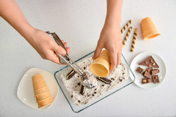 Woman preparing tasty ice cream on white background, top view