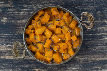 Baked yellow pumpkin with honey, anise, olive oil and spices on a plate on the wooden table. Vegetarian food. Closeup