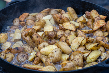 Roast potatoes in a large pan.Young potatoes are fried in oil, street food