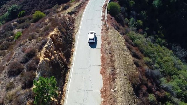 4k-Aerial view of white car driving on Mountain , drone follow white highlander car driving on top of the mountain on a road with forest and moutain background, in a beautiful day