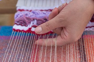 Hands of woman weaving color pattern on traditional hand-weaving wooden loom, Ukraine. Closeup