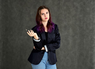 Studio portrait of a pretty brunette student girl with long hair in a jacket on a gray background. Smiling at camera with emotions in various poses.