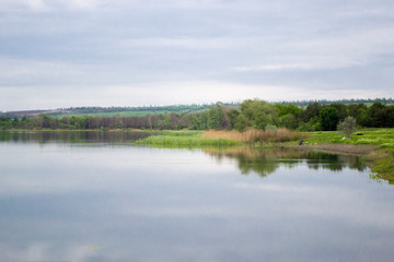View of the opposite shore of the lake at dusk. Beautiful, serene summer weather. Time after sunset. Copy space.