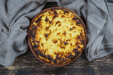 Sweet cottage cheese casserole with raisins and semolina on wooden table. Ceramic bowl with baked cottage cheese casserole , closeup, top view
