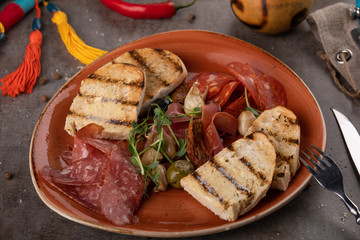 Italian smoked ham Prosciutto and sausage with crostini bread and specialties for antipasti on plate served at restaurant