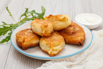 Plate with fried pies and greens on wooden boards.