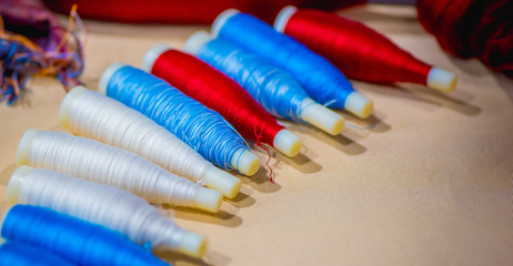 Colorful Weaving shuttle on brown fabric, Reels of threads background, Textile industrial concept.