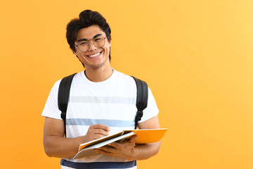 Portrait of handsome Asian student on color background