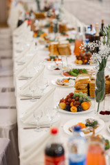 Tables setting at a luxury wedding. Table for guests. Dishes and drinks. Floral decorating, white chairs and table. Wedding table preparation. top view. vertical photo