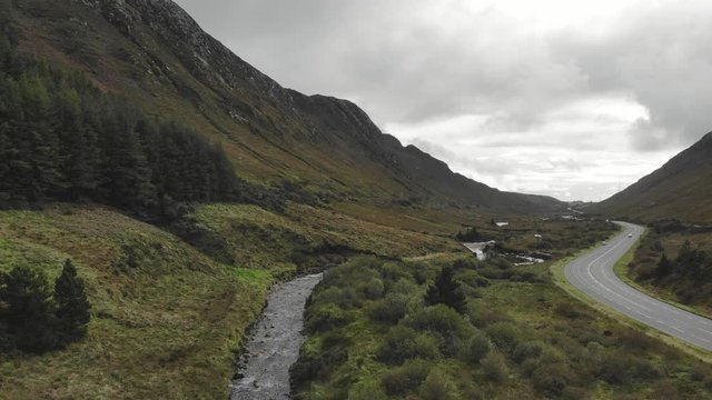 Mountain pass with valley and bandy river and road next to it. Aerial view lift up