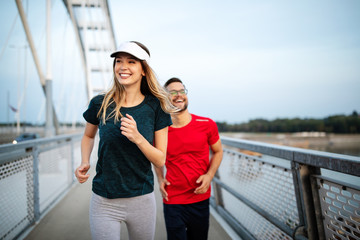 Early morning workout. Happy couple running across the bridge