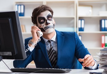 Businessmsn with scary face mask working in office