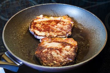two fried piece of meat in frying pan on range