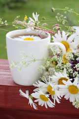 Obraz na płótnie Canvas A cup of tea with daisies bouquet 