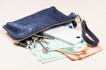 handbag with phone, keys and many euros on table