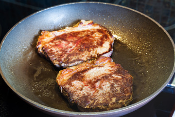 two roasted piece of meat in frying pan on range