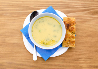 Top view of yellow vegetable soup in a bowl on a wooden table