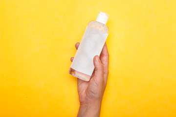 Makeup remove skin care. Closeup woman holding remover bottle. Woman cleaning her face with lotion. Woman holding bottle with skin care product.