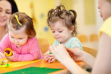 Fototapeta premium Children toddlers playing with plasticine at kindergarten or playschool
